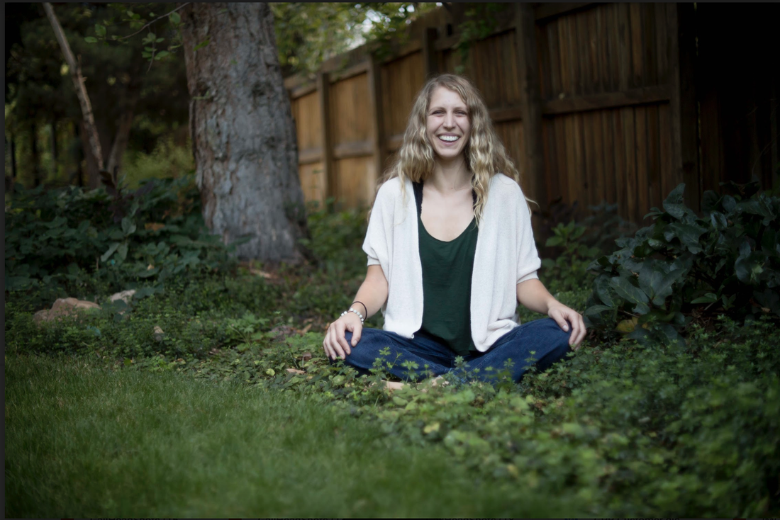 smiling woman sitting cross-legged in nature